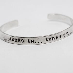 silverarmband med texten andas in andas ut på vit bakgrund