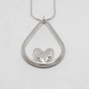 droppformat silverhalsband med hjärta i mitten på vit bakgrund