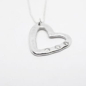 silverhjärta med stenar på vit bakgrund