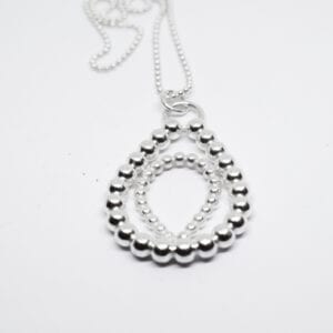 stort silversmycke i kultråd med vit bakgrund